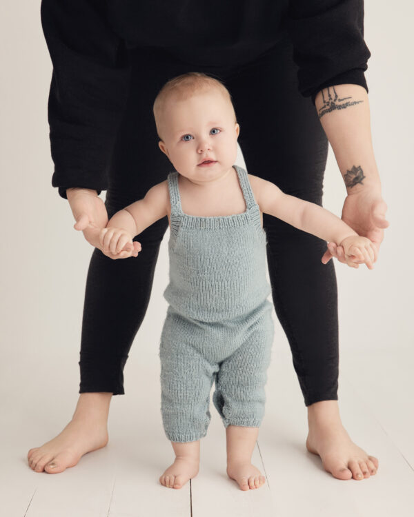 Portrait d'un bébé d'un an qui tient debout avec sa maman