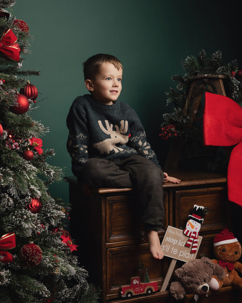 Garçon pris en photo devant un décor de Noël