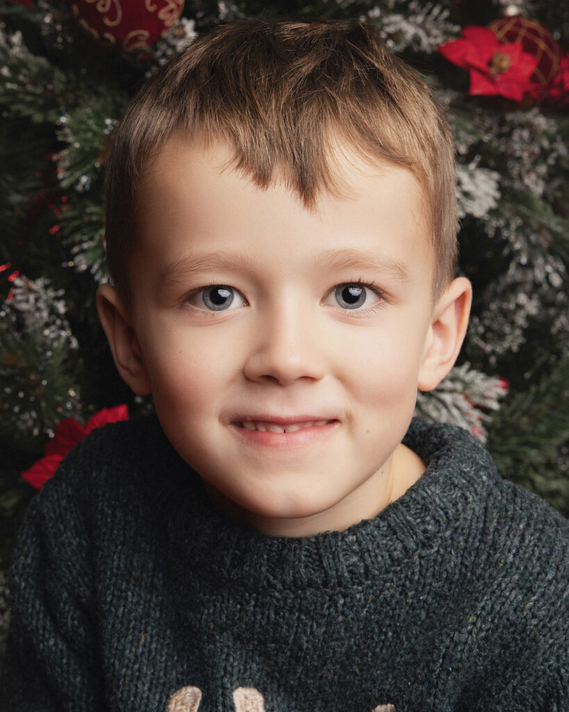 Portrait d'un enfant devant un sapin de Noëé